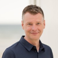 Photo of a man smiling looking at the camera.